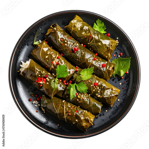 Stuffed vine leaves with rice on a black plate garnished with parsley and spices top view isolated white background