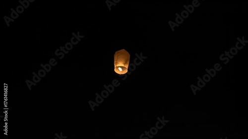 A Single Glowing Paper Lantern Ascends Peacefully into the Pitch Black Night Sky