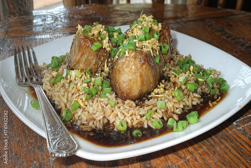 White rice with tender meat and herbs on a square plate. Elegant Asian cuisine.