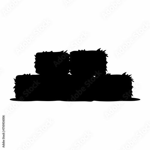 Black silhouette of stack of hay bales on the ground in rural area