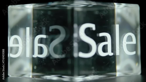 Clear cube with Sale text reflected and distorted on its sides