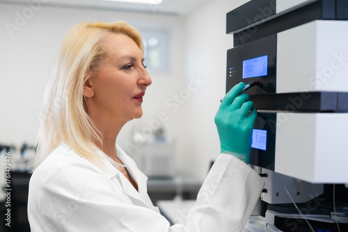 Scientist in lab coat using high-performance liquid chromatography instrument for precise analytical chemistry research.