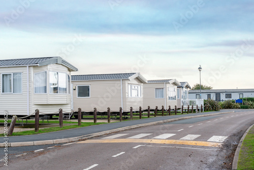 Temporary homes line a quiet road at a holiday park during early morning light