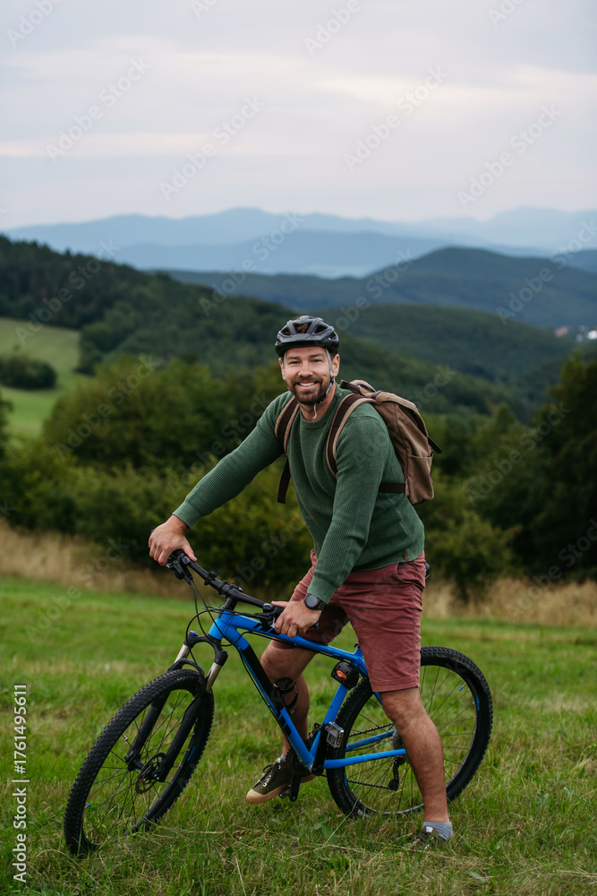 Obraz premium miling mature man with bicycle enjoying countryside ride at sunset.