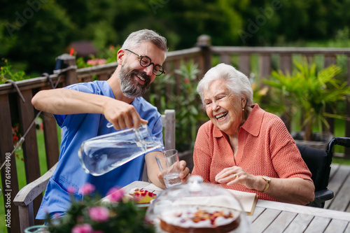 Obraz na płótnie Caregiver pouring fresh wather to elderly woman.