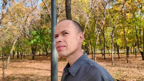 Slow-motion video of a forty-year-old man in an autumn park looking at the sun.