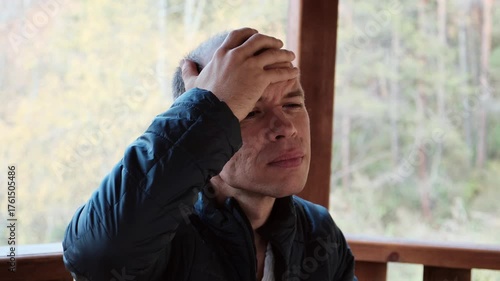 A middle-aged man touches his head with a pained expression, showing signs of a severe headache. Perfect 4K video for health, stress, and medical-related content.