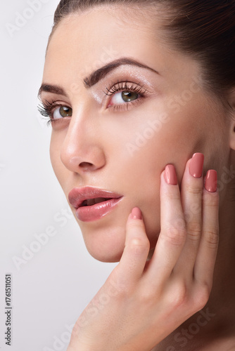 Beautiful Young Woman with Clean Fresh Skin. Close up Portrait.  Fashion Model Girl Face. Perfect Skin. Professional Makeup. Fashion shiny highlighter on skin, sexy gloss lips. Perfect manicure.