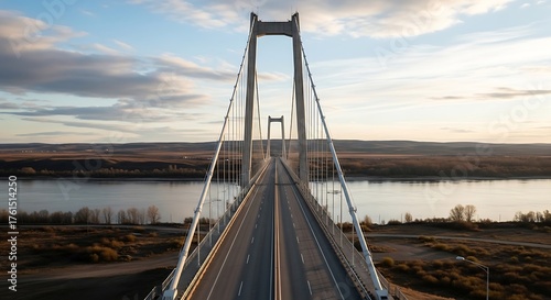 Modern suspension bridge spanning a wide river at sunset
