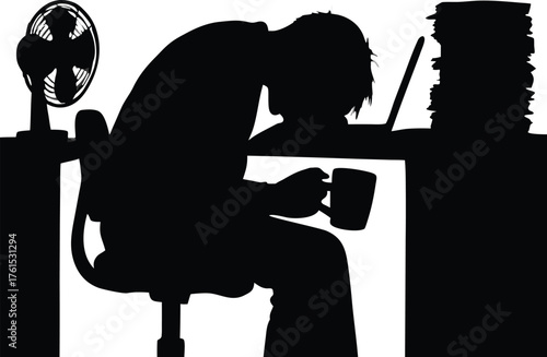 a person working late at a desk with a fan