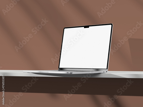 Minimalistic laptop with blank screen on a desk, with soft lighting and shadow play.
