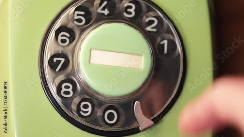 Close-up view of a hand dialing numbers on an old rotary phone. Retro plastic phone.