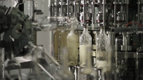 Automated bottling machine filling wine into glass bottles on production line