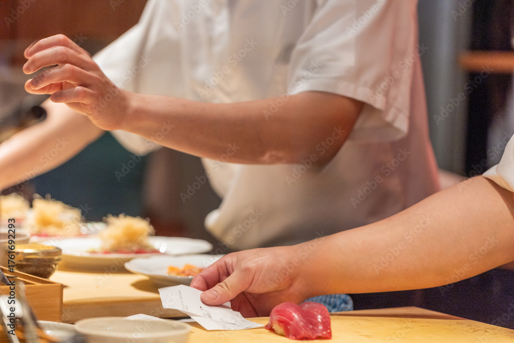 Obraz premium Chef preparing sushi with fresh ingredients on wooden countertop in restaurant