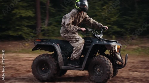 muddy ground, forest dirt, terrain driving. Driver on ATV leans into sharp turn on forest path, dirt flying everywhere.