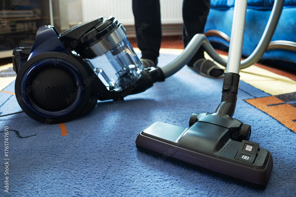 Fototapeta premium Man cleaning carpet with vacuum cleaner at home, closeup