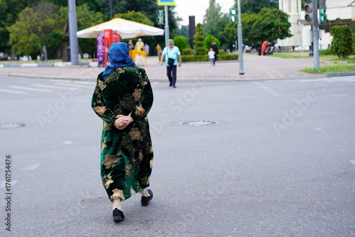 Elderly woman walking in traditional clothing on a city street during daytime