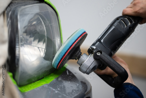Person polishing car headlight with power buffer
