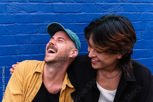 Happy gay couple enjoying in front of wall