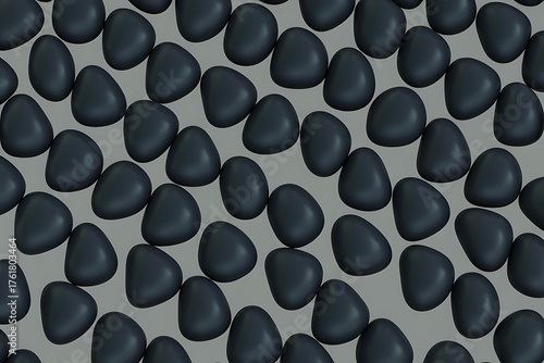Dark, smooth pebbles densely arranged over a light gray, textured background pattern.