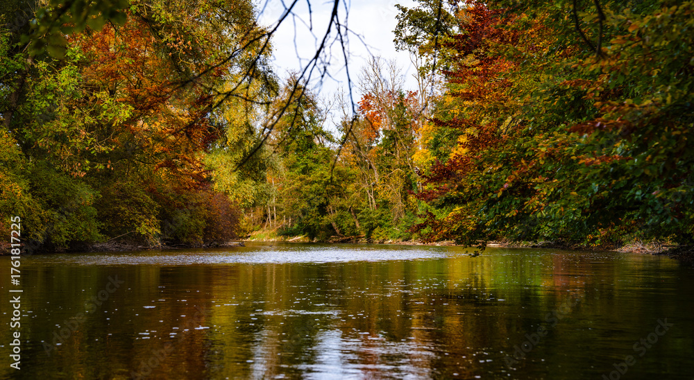 Fototapeta premium Amper River Near Fuerstenfeldbruck Munich Bavaria: Peaceful Autumn Landscape With Flowing Water Surrounded By Colorful Trees And Natural Riverbank