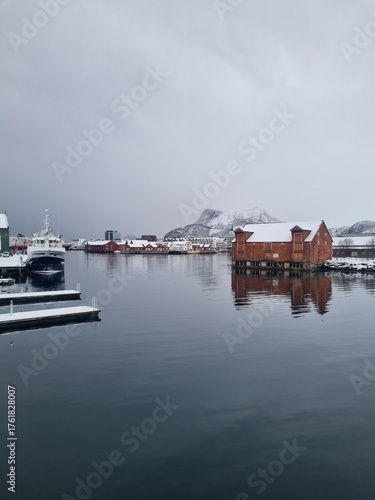 Svolvaer harbor panorama with boats, traditional and modern buildings, Snowy mountain on horizon. Lofoten islands, Norway.