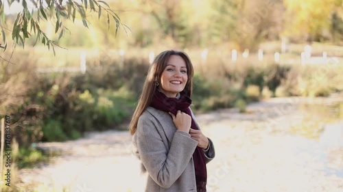Portrait of a young beautiful woman in a burgundy scarf inhaling and exhaling fresh air, taking a deep breath, and looking at the camera. She smiles. Healthy lifestyle concept.