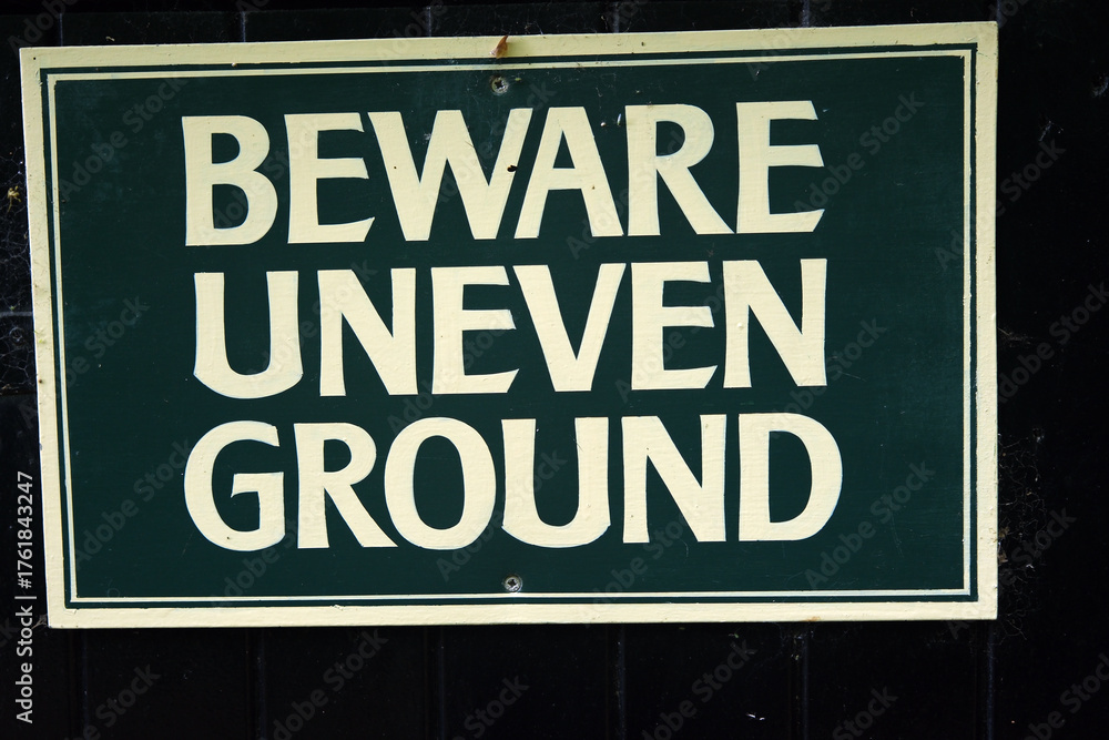 Obraz premium Close-up of a Beward Uneven Ground sign warning pedestrians of potential hazard in outdoor area.