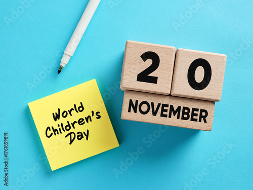 Wooden calendar showing november 20 for universal children's day with white marker pen and yellow sticky note