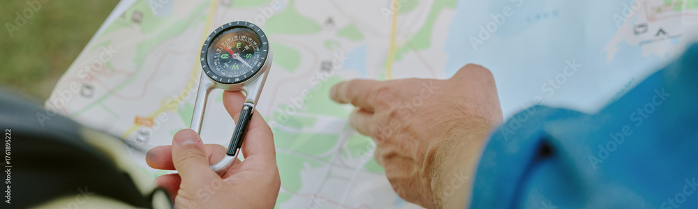 Obraz premium Hands of unrecognizable person pointing at paper map outdoors, focusing on navigation and route planning during adventure activity