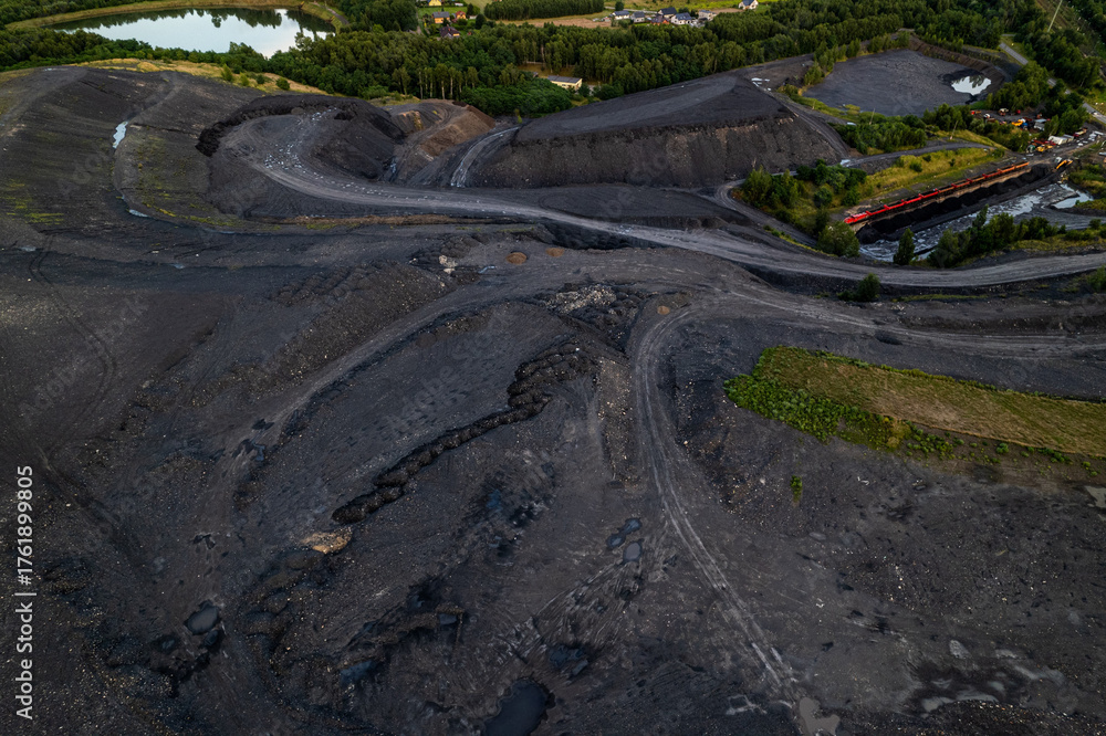Fototapeta premium Red freight train transporting coal wagons railway track aerial view Rybnik Poland mining dump industrial vegetation horizontal landscape cargo