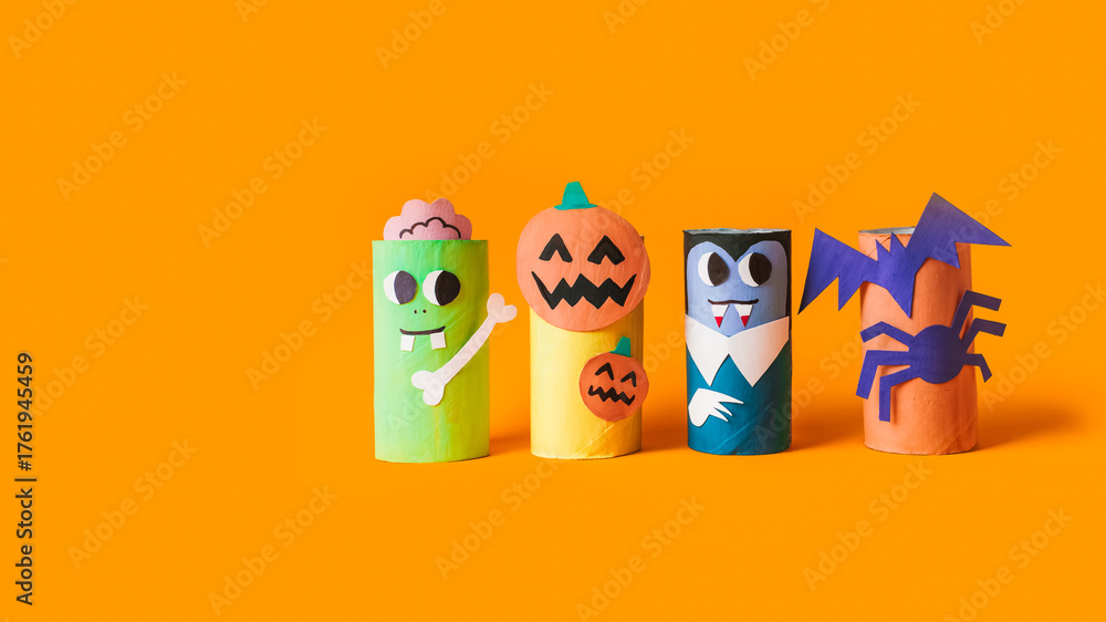 Fototapeta premium Halloween monsters from toilet paper roll tube, easy DIY handmade decorations idea. Paper toys zombie and vampire on yellow background. Kids creativity, easy eco craft, step by step, place for text