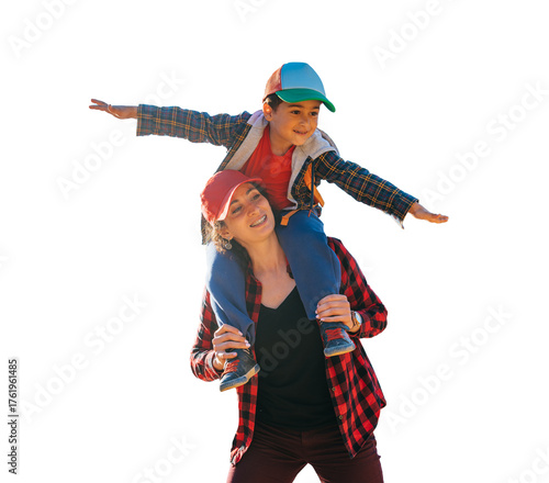 Happy little boy sitting on mom's neck spreads hands like airplane against transparent background , traveling. Family leisure outdoors, childhood. Tourism. young woman plays with son.