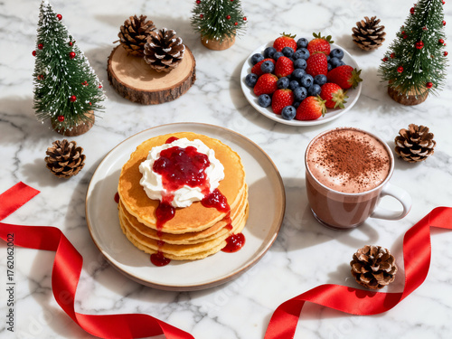 A stack of festive golden pancakes topped with whipped cream and berry jam, served with fresh berries and hot chocolate, against a bright marble backdrop with decorations.