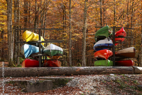 Canvas Print Bright kayaks and canoes are stacked on metal racks in an autumn forest