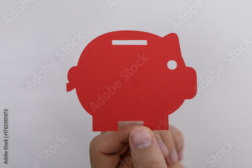 A hand holds a red piggy ba...