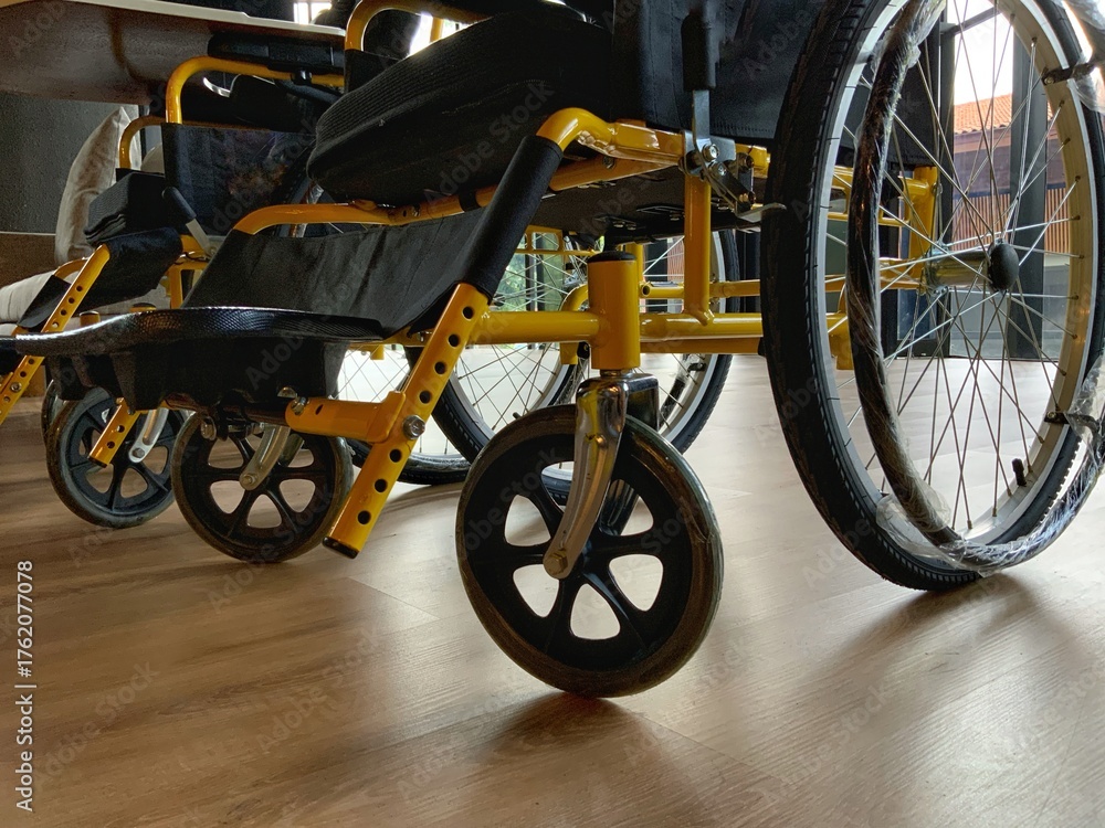 Fototapeta premium Row of modern yellow wheelchairs ready for use, symbolizing mobility, care, and accessibility in a clean, bright indoor space.