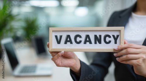 Wallpaper Mural A close up of a person in smart casual office attire holding a sign that says VACANCY in large clear letters, modern office background with blurred Torontodigital.ca