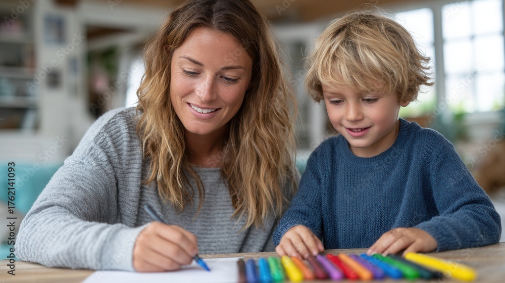 Obraz premium A mother and her young son are happily drawing together at home, showcasing creativity and bonding in a cozy environment.