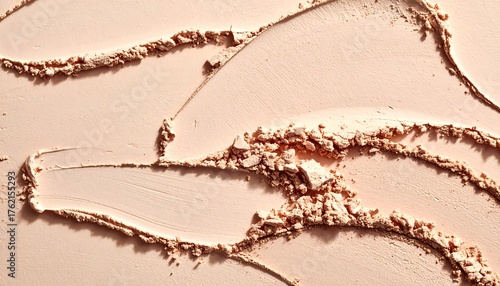 An abstract close-up view displaying the texture of light pink cosmetic powder that has been smoothed onto a surface in brushstrokes