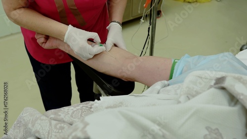 Medical professional wearing protective gloves inserting intravenous cannula into patient's arm, preparing for surgical procedure medication or fluid administration