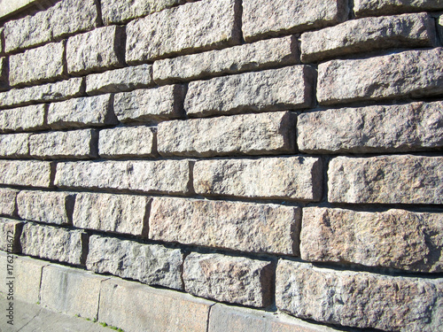 Full frame textured stone wall in sunlight.