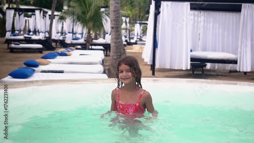 Six year old girl enjoying tropical vacation at resort pool