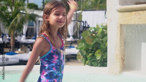 Six year old girl enjoying tropical vacation at resort pool