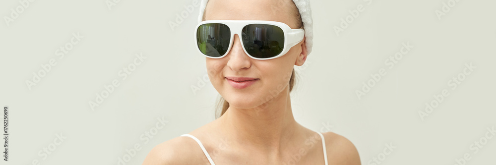 Fototapeta premium Caucasian young female smiling wearing large white sunglasses with neutral background.