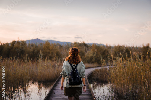 Adventurous hiker girl walking on wooden bridge over mountain lake