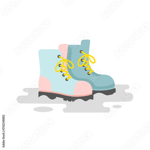 Colorful winter boots standing in slush with puddles on ground  
