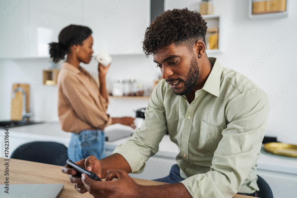 Fototapeta premium African american man using smart phone in kitchen
