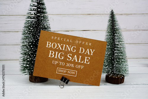 Festive display with small decorative Christmas trees with "Special Offer Boxing Day Sale up to 30% off, Promotion Holiday Sale Event