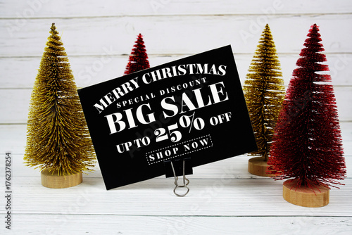 Festive display with small decorative Christmas trees with "Special Offer Merry Christmas Big Sale up to 25% off, Promotion Holiday Sale Event